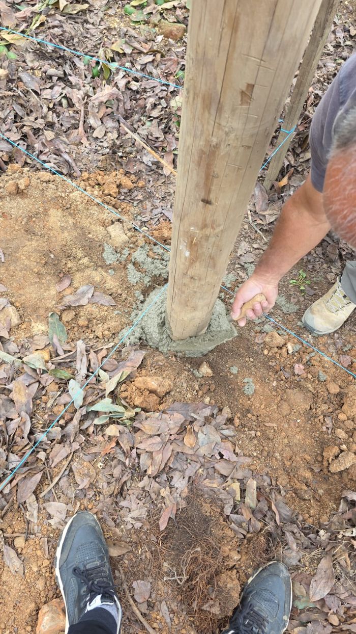 Mano terminando la base de concreto de un poste